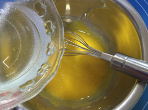 将热水玉米油的混合物缓缓加入蛋黄糊中，加入的同时用手动打蛋器搅拌