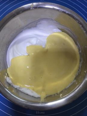 将翻拌好的蛋黄糊倒入剩余蛋白糊中，用刮刀翻拌均匀。