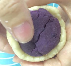 酥皮分好后就开始包入馅料了，取一个酥皮按扁，再用擀面杖擀成圆形，然后把馅包住，搓圆