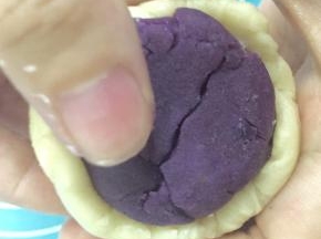 酥皮分好后就开始包入馅料了，取一个酥皮按扁，再用擀面杖擀成圆形，然后把馅包住，搓圆