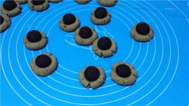 放凉的饼干将奥利奥球摆在凹槽上，用黑巧克力粘住