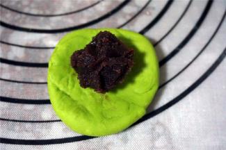 将面团按扁，包入适量的豆沙馅料，收口朝下。