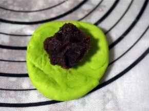 将面团按扁，包入适量的豆沙馅料，收口朝下。