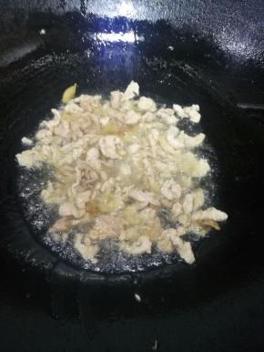 8.炒至猪肉变色后，倒入切好的大蒜，炒出大蒜的香味