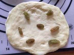 拿出一个面团，放入葡萄干，揉成圆面团