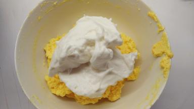 取1/2的蛋白霜加入到黄油糊中，用橡皮刮刀用翻拌的手法拌匀。