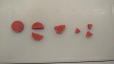 蛋糕烘烤期间我们来做装饰的材料。取一根火腿肠，切成2mm左右的薄片，对半切开之后再切成3个三角形，做小鸡的嘴。