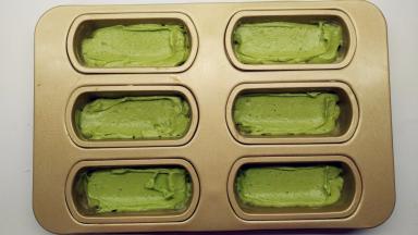 将抹茶面糊平均地挤入到模具中，用刮刀稍微抹平。