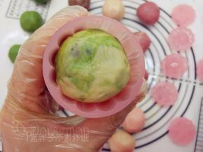 取出月饼模，放入花片，将它卡住。月饼面团稍微搓成圆柱形，放入模具中，稍加用力按压。