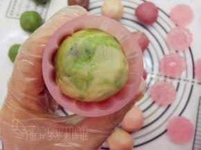 取出月饼模，放入花片，将它卡住。月饼面团稍微搓成圆柱形，放入模具中，稍加用力按压。