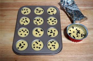 在迷你12连杯不粘马芬模具中挤入9分满的蛋糕糊，多出来约2个迷你杯的量，用一个稍大的蛋糕杯装着即可。然后分别撒上适量的耐高温巧克力豆。