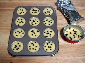 在迷你12连杯不粘马芬模具中挤入9分满的蛋糕糊，多出来约2个迷你杯的量，用一个稍大的蛋糕杯装着即可。然后分别撒上适量的耐高温巧克力豆。