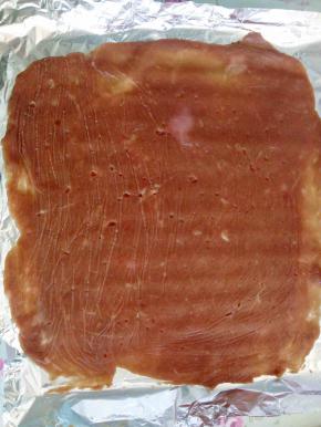 入味后的肉泥取一部分放到锡纸上面盖一层保鲜膜擀成均匀的薄片，不要太厚也不要太薄。跟我们平时吃的肉脯厚度厚一点点就可以，因为烤好后肉脯会缩一些，那时候的厚度是刚刚好的。