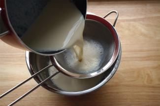 然后把和蛋清混合后的奶液过筛。把过筛后的奶液慢慢倒回锡纸小碗里。