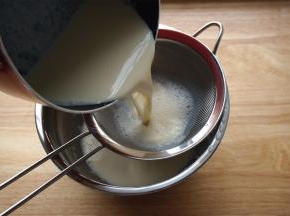 然后把和蛋清混合后的奶液过筛。把过筛后的奶液慢慢倒回锡纸小碗里。