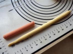 取一份面团，揉光滑后，搓成长条状，长度约为火腿肠的两倍。