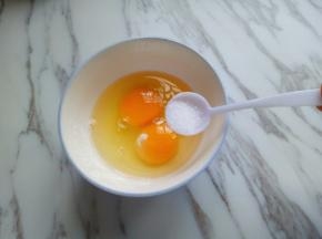 把鸡蛋打在碗里，加入少许盐。