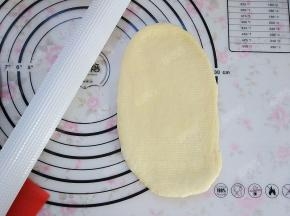 醒发好的面团按扁，光滑面朝上擀成长条形