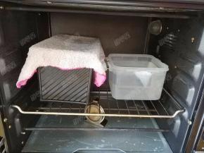 土司盒盖上湿毛巾放入烤箱，烤箱内放入一碗温水进行二发，发酵温度38°