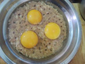 在肉馅上用筷子戳均匀的洞，磕入鸡蛋