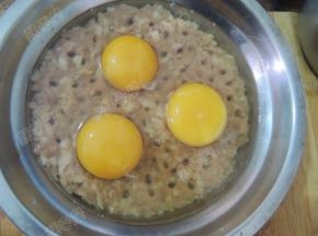 在肉馅上用筷子戳均匀的洞，磕入鸡蛋