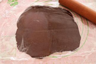 将可可色面团铺在硅胶垫上，上下各覆盖一层保鲜膜，用擀面杖擀成厚度大概3mm厚的面皮；