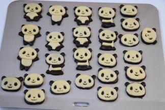 用同样的方式将原色面团擀成薄皮后用模具按压出脸部外形、表情部分、腹部部分，然后依次摆在可可面团的熊猫形状上；