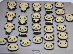 用同样的方式将原色面团擀成薄皮后用模具按压出脸部外形、表情部分、腹部部分，然后依次摆在可可面团的熊猫形状上；