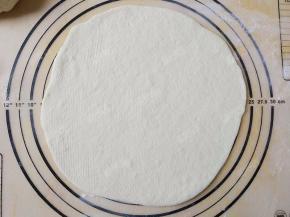 取一份面团擀成厚薄均匀的圆形饼底，大小刚好是硅胶垫上的九寸