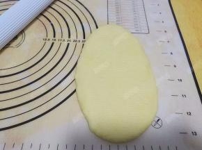 取一份面团压扁，用擀面杖擀开成长条形