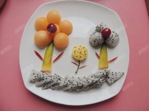 火龙果籽点缀在圆形芒果花上做成向日葵，底部用三角形的火龙果片装饰一下就完成了