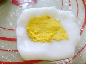 取适量白色冰皮面团，包裹适量南瓜粉，充分揉匀。