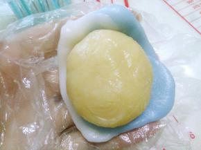 取20g冰皮，用手压平，中间略厚，边缘薄。中间放入白芸豆奶香馅，像包汤圆一样，虎口轻推收口。