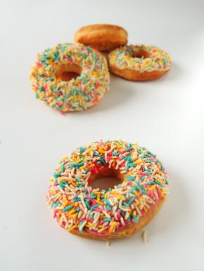 炸好的甜甜圈完全冷却以后，粘上融化的巧克力，撒上彩色糖针装饰，就可以吃了