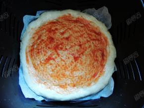 在饼底均匀涂上一层番茄沙司，外围一圈不用涂，再撒上一些披萨草