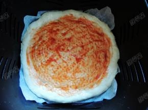 在饼底均匀涂上一层番茄沙司，外围一圈不用涂，再撒上一些披萨草