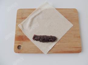 取一张春卷皮，在春卷皮的下半部分放上豆沙馅，把豆沙馅码成需要的长度和宽度