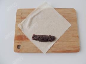 取一张春卷皮，在春卷皮的下半部分放上豆沙馅，把豆沙馅码成需要的长度和宽度