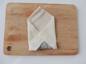 卷住馅料后再把左右两边的春卷皮向中间折，封住两端的开口