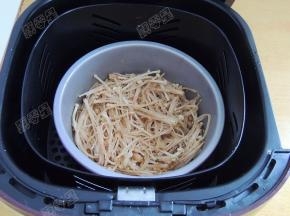 将盛有金针菇的容器放入空气炸锅的炸篮里
