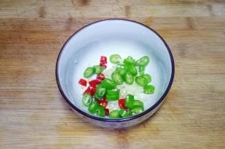 将蒜去皮，压成蒜泥，红辣椒切小段，青辣椒切成辣椒圈放入碗中