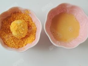取一个包好的面团先沾鸡蛋液，再裹面包糠。