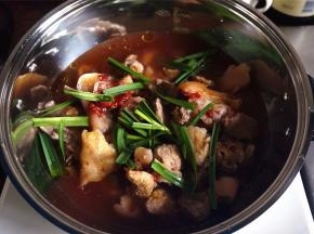 然后放入猪手，淋上南乳汁，放入盐，糖，生抽，老抽，料酒，表面铺上大蒜叶，从四周加入1000毫升清水。