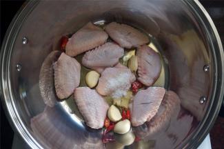 锅里下油，然后放入姜蒜辣椒以及鸡翅。