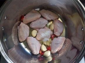 锅里下油，然后放入姜蒜辣椒以及鸡翅。