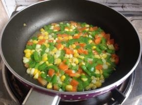 放入玉米粒、胡萝卜粒和青椒粒，加入盐和糖翻炒片刻，放入适量的水煮3分钟左右