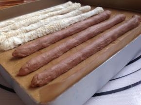 搓成长条形，白色面团在芝麻上搓长，使面团粘上芝麻