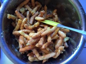 将糖浆倒入炸好的胚条中，撒上少许白芝麻，趁热快速拌匀，尽量使每一根胚条蘸上糖浆