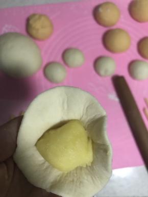 16.取一个白色面团擀薄，包入奶黄馅封口。