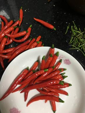 用剪刀剪掉小米椒的头，烂的和破口的辣椒要捡出来不能泡